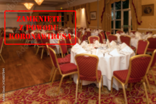 Defocused, blurred view of interior of an upmarket wedding venue or restaurant, empty and closed with Polish notice Closed due to Coronavirus