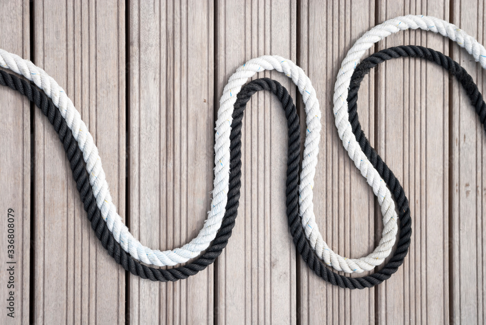 Obraz premium Black and white nautical ropes curving together outdoors on a wooden background
