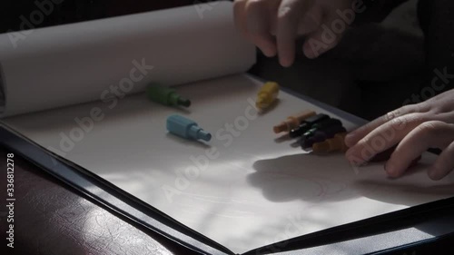 A child draws with pencils on white paper.  A little boy learns to draw. 