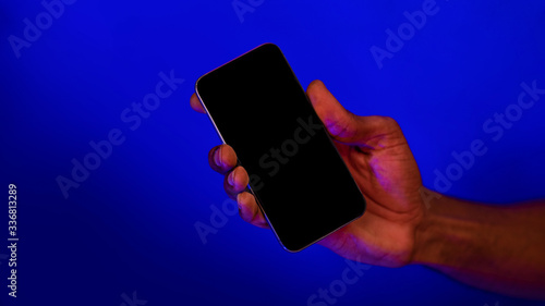 Unrecognizable Man Holding Smartphone Over Blue Background, Closeup, Mockup
