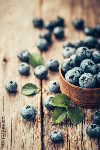Freshly picked blueberries in wooden bowl on wooden background. Healthy eating and nutrition.