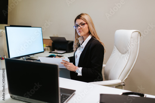 Young attractive businesswoman with glasses writes on her desk. An office job