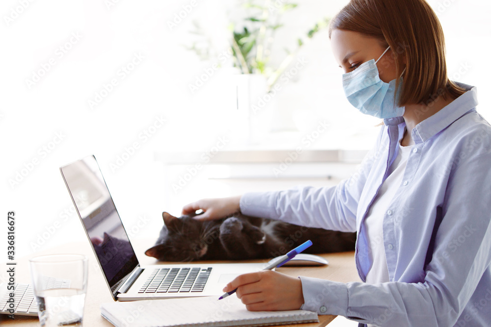 Woman employee in mask with laptop computer in self isolation working from home, coronavirus covid-19 quarantine. Remote working of business worker, online education. Prevention of virus spread Woman employee in mask with laptop computer in self isolation working from home, coronavirus covid-19 quarantine. Remote working of business worker, online education. Prevention of virus spread