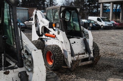 Two white skid steer loader at a construction site waiting of work. Industrial machinery. Industry.