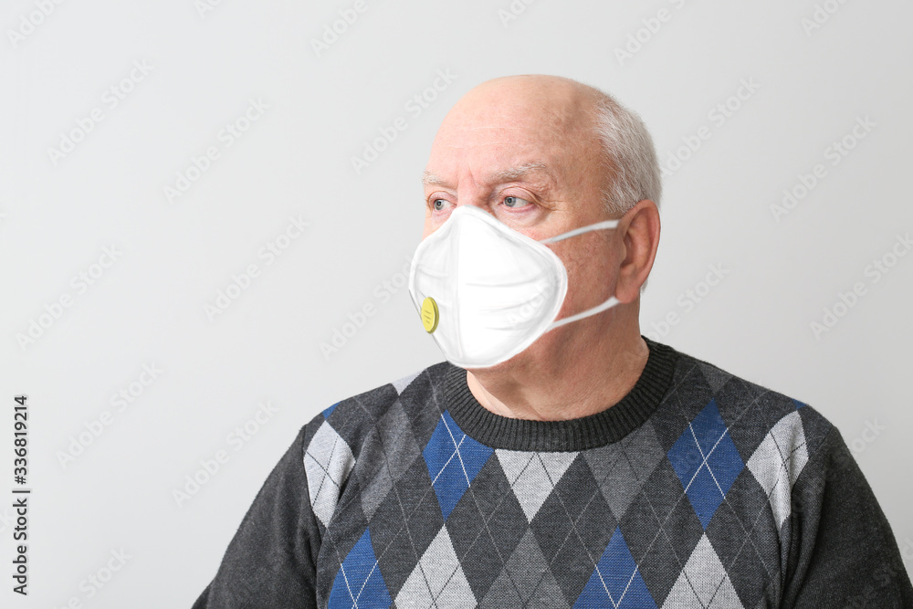 Portrait of elderly man wearing protective mask on light background. Concept of epidemic Portrait of elderly man wearing protective mask on light background. Concept of epidemic