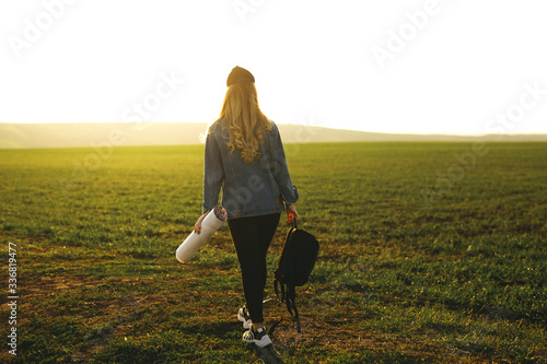 Portrait of a traveler girl looking direction on world map, bright orange sunset light, traveling throughout World. Freedom and active lifestyle concept, adventure, trip.