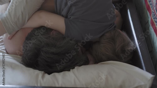 little boy wake up their dad.  Cute toddler son and father sleeping together on bed in bedroom at home.