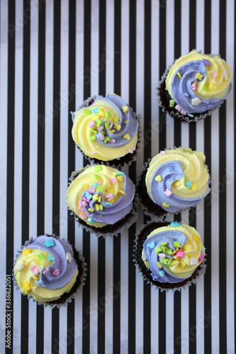 Top view of yellow and purple easter cupcake on lined background