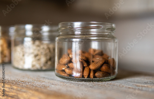 Sunflower seeds, walnut and almond in a jars which standing on a white vintage table with a kitchen on background. Nuts is a healthy vegetarian protein and nutritious food. Nuts on rustic old wood.
