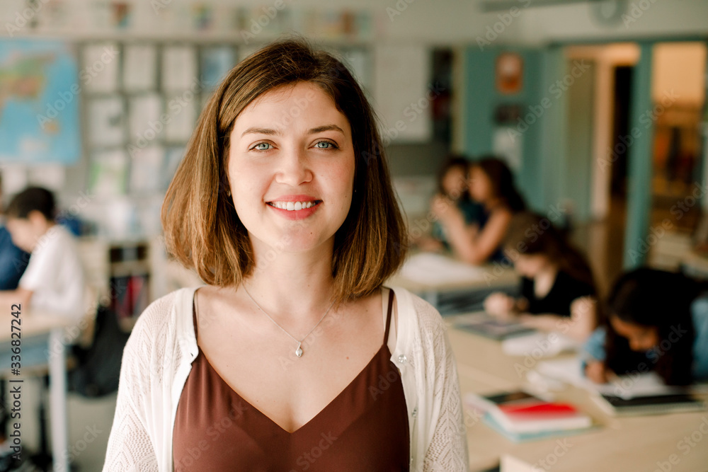 Portrait of smiling female teacher standing in classroom Portrait of smiling female teacher standing in classroom