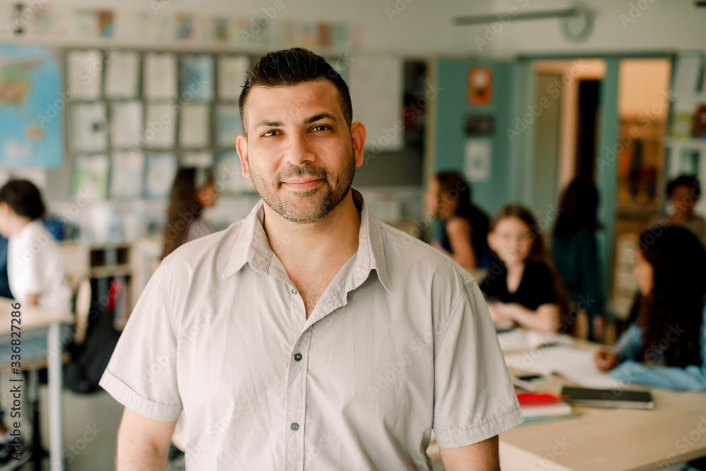 Portrait of smiling male tutor standing in classroom Portrait of smiling male tutor standing in classroom
