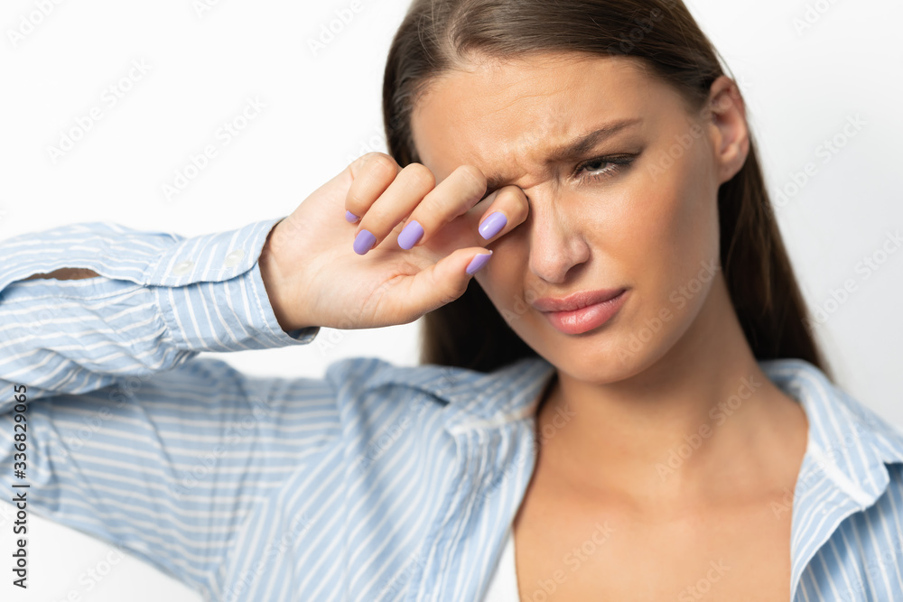 Woman Touching Aching Eye Standing On White Background, Studio Shot Woman Touching Aching Eye Standing On White Background, Studio Shot