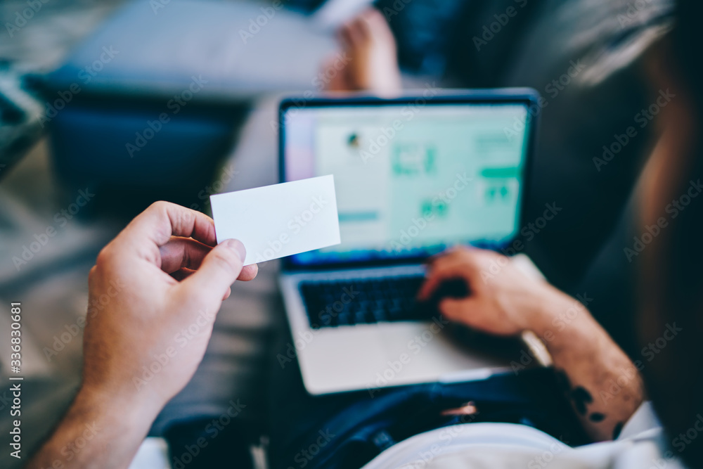Man looking at business card working with laptop Man looking at business card working with laptop