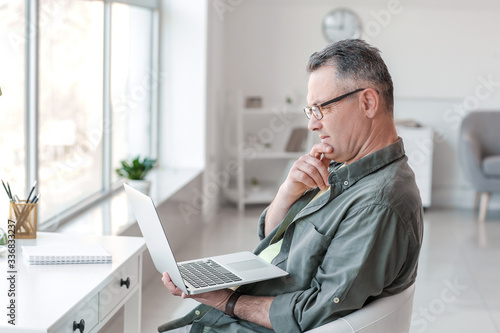 Mature man using laptop at ...