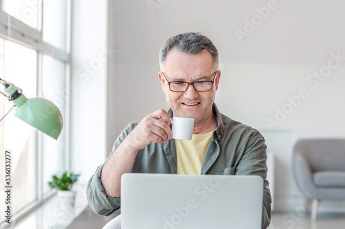 Mature man using laptop at ...
