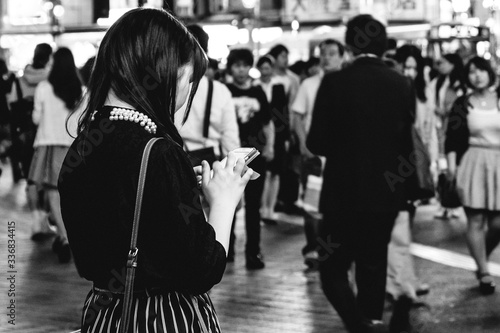 Girl form back using phone in crowd at Tokyo downtown streets (Shibuya) (in black and white) 