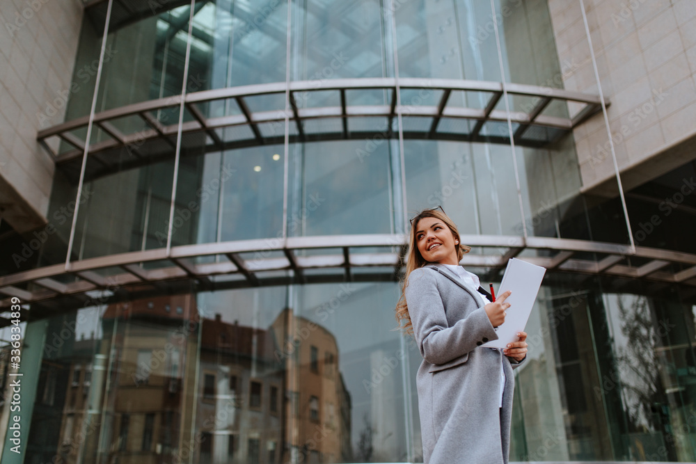 Young attractive caucasian businesswoman with notebook in front of company Young attractive caucasian businesswoman with notebook in front of company
