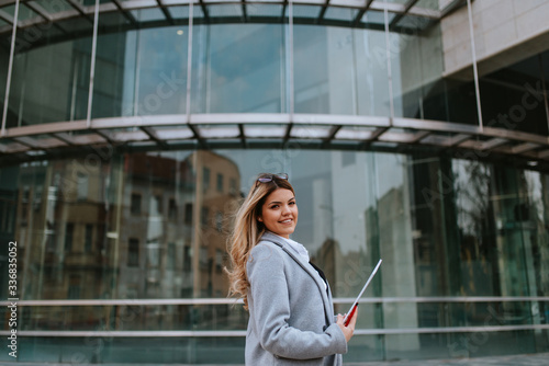 Young attractive caucasian businesswoman with notebook in front of company