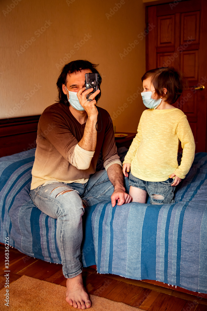 daddy and daughter in medical masks, studying art photography, at home during quarantine, due to the covid-19 pandemic daddy and daughter in medical masks, studying art photography, at home during quarantine, due to the covid-19 pandemic