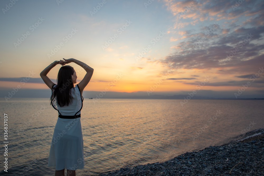 Fototapeta premium 夕日の浜辺を歩く女性