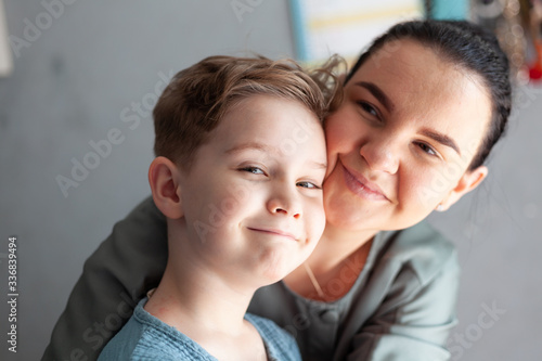 Child with autism and down syndrome smiles happily in the arms of a happy mother Dual Diagnosis