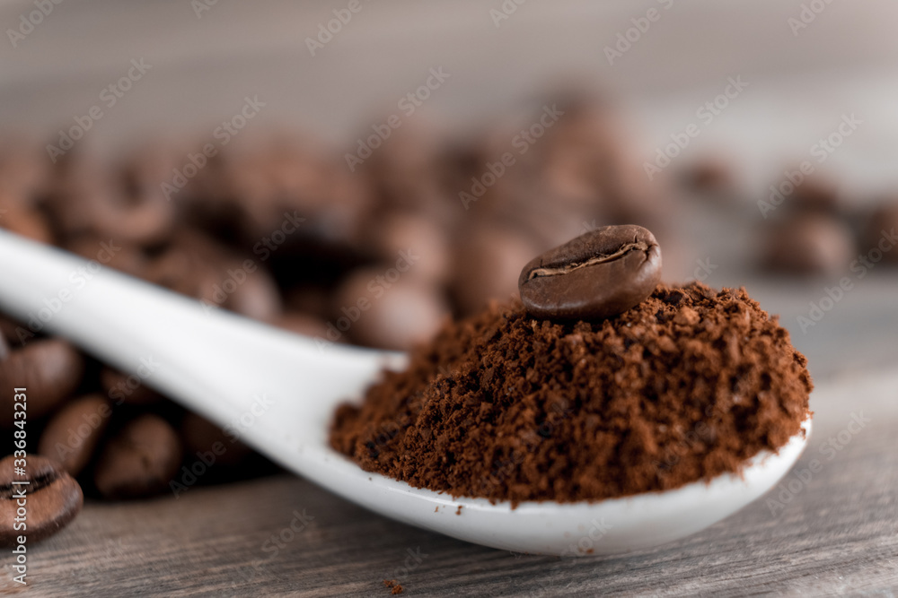 white ceramic spoon with ground coffee on a wooden background Fried Arabica grains white ceramic spoon with ground coffee on a wooden background Fried Arabica grains