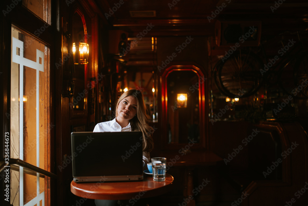 Attractive young caucasian blonde businesswoman working on laptop in cafe