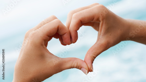 love sign on blue ocean water background. female hands show a symbol © Artem