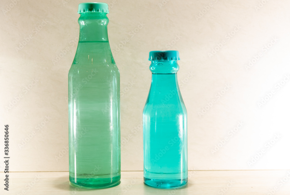 Colored glass bottles with natural water on light and illuminated background Colored glass bottles with natural water on light and illuminated background