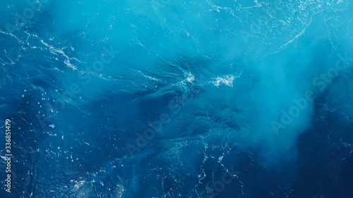 close-up wavy blue ocean surface, foam streaks on sea water