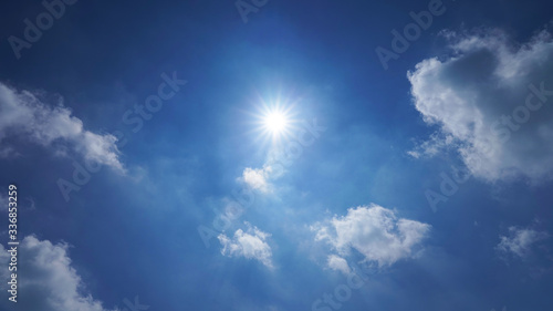 blue sky with white clouds and bright sun. dramatic summer sky background © Artem