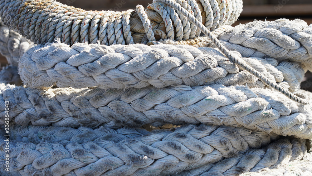 Large ship ropes folded to dry on the shore. mooring bays stacked by a bay on a sunny day