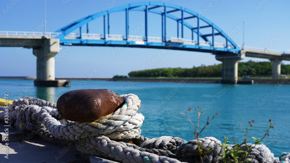 Fototapeta premium berth in the passenger port. Mooring points of the ship are fixed in the port. bright rusty bollard with ship ropes. against the background of a passenger ship and a bridge