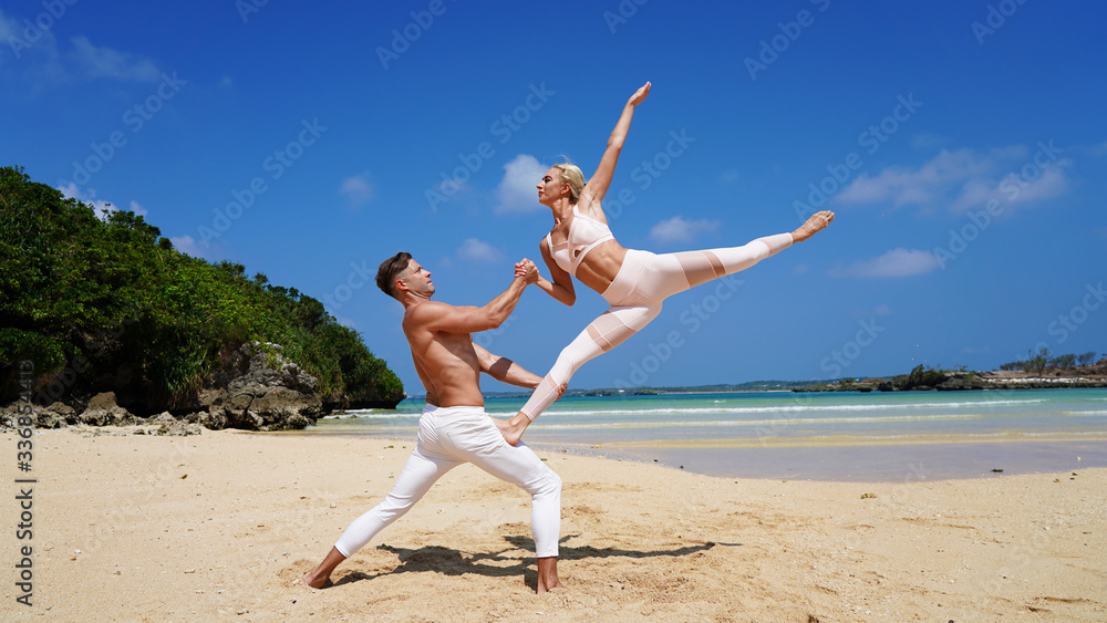couple of beautiful dancers on the shore of a paradise beach perform acrobatic pose and split couple of beautiful dancers on the shore of a paradise beach perform acrobatic pose and split