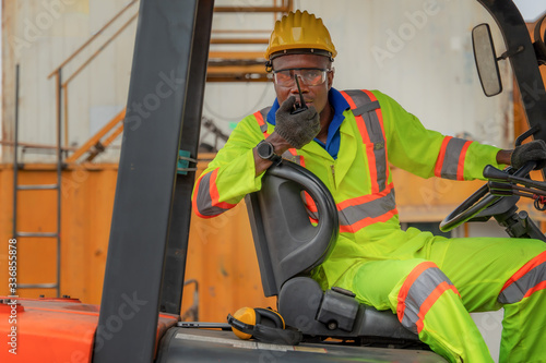 industial background of african american forklift driver driving forklift a loading area at containers yard and cargo