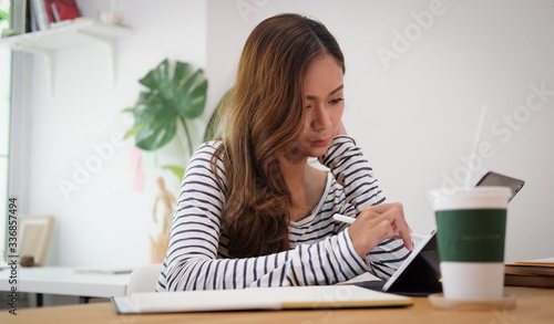Woman working from home on laptop computer while sitting at the living room, drinking coffee
