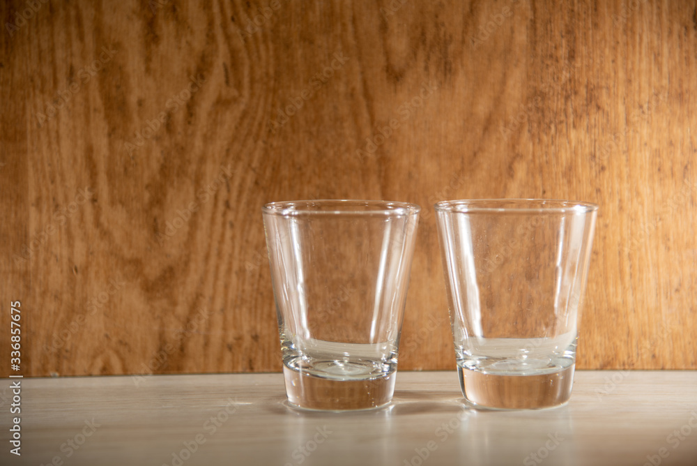 Glass cups on clear surface and woody background Glass cups on clear surface and woody background