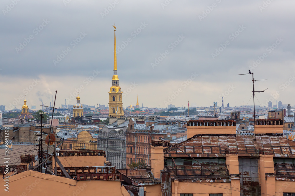 Fototapeta premium Beautiful top view of the historic center of St. Petersburg, the roofs of buildings and the high bell tower of the Peter and Paul Cathedral with a golden spire. Saint-Petersburg, Russia.