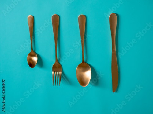 set of tableware. Knife fork spoon made of yellow metal imitating gold on a blue background