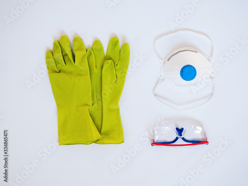 white protective medical mask with clipping path on white background, green gloves, safety glasses © galitsin