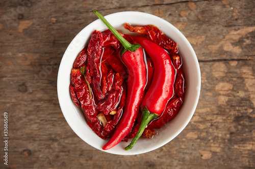 Group of chili peppers and dried chili inside white bowl on wooden table