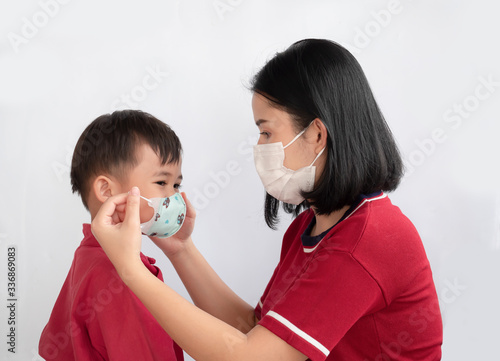 Portrait of mother and son are showing love and wearing protective mask trying to protect from virus epidemic over gray background.