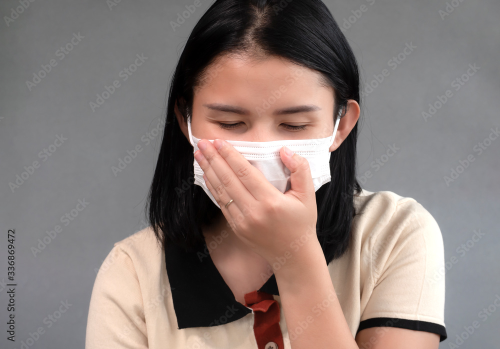 Coughing pain women and wearing mask trying to protect from coronavirus epidemic over gray background. Coughing pain women and wearing mask trying to protect from coronavirus epidemic over gray background.