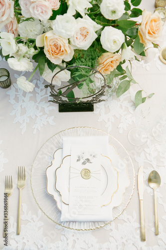 Fotografie A beautiful tablescape with white and gold china, gold utensils and a floral cen