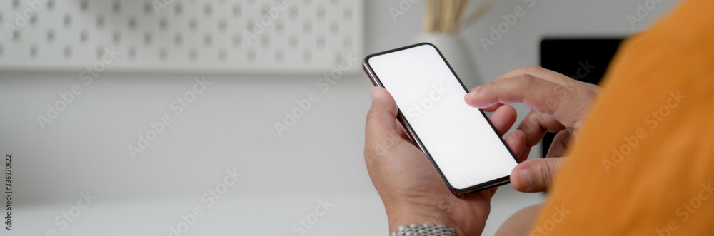 Cropped shot of male freelancer touching on mock-up smartphone at home office Cropped shot of male freelancer touching on mock-up smartphone at home office