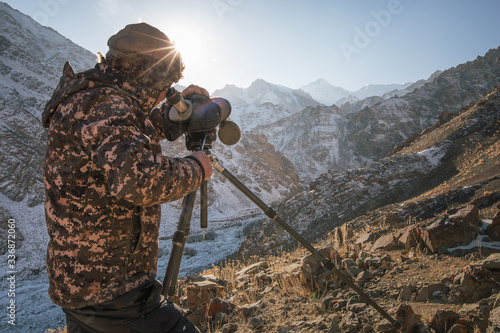 Spotter looking through a scope for snow leopards and other wildlife, Hemis National Park, India.