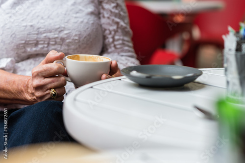 anonymous senior woman with coffee cup  sitting in a cafe