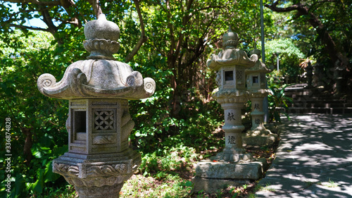 ancient Japanese statues, lanterns on the road through the jungle to a Buddhist temple. creepers and jungle over the road to a Japanese traditional religious temple. ancient temple on island Okinawa