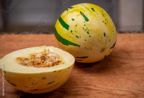 Melon fruit (Cucumis mello L.) halved on a woody background