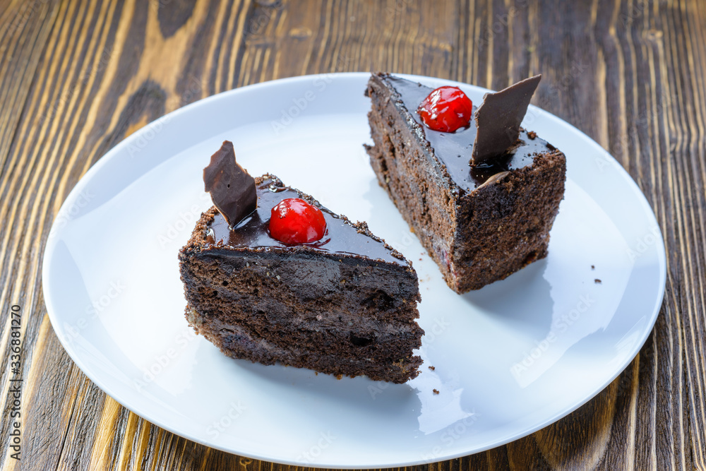 two chocolate cakes with cherries on a white plate two chocolate cakes with cherries on a white plate